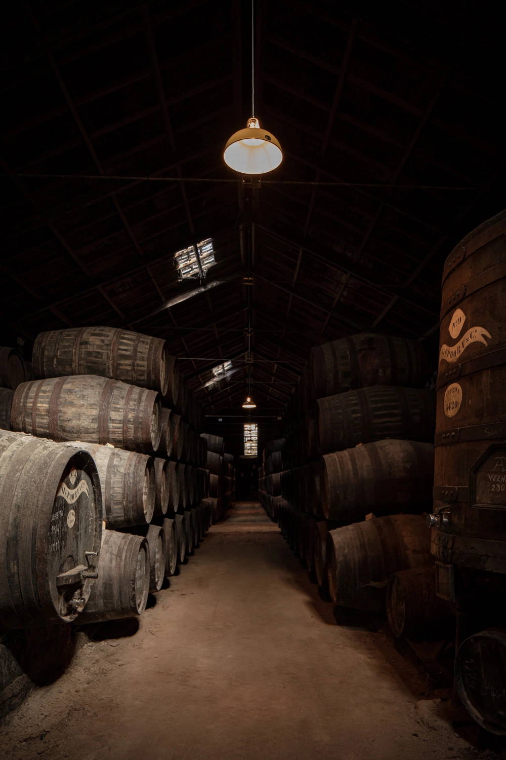 A Deep Yellow lampshade hanging in front of wine casks