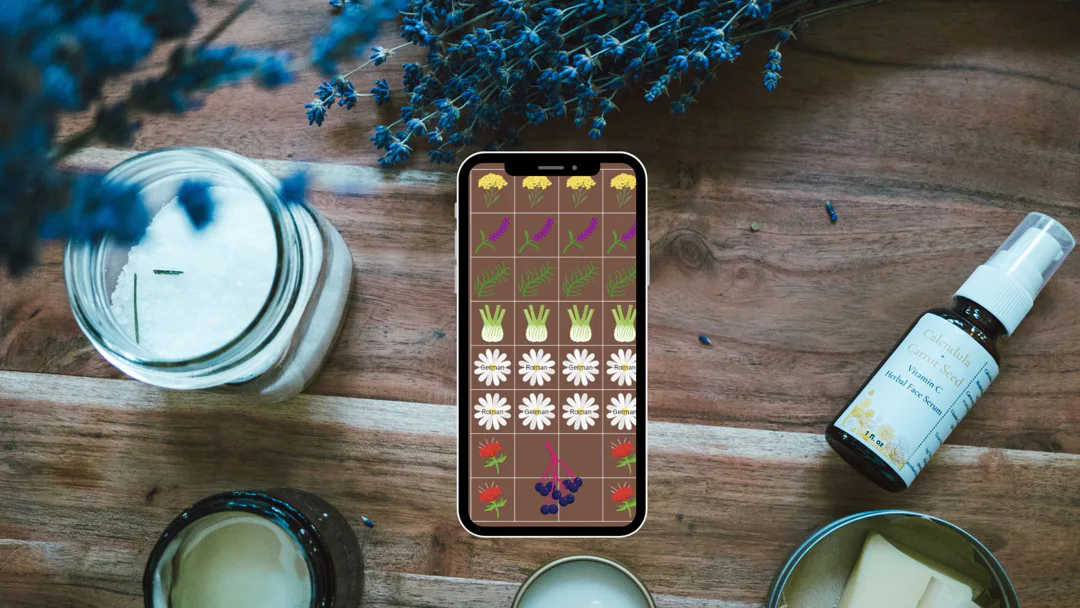 A phone showing a Planter garden plan surrounded by candles, bath products, and lavender