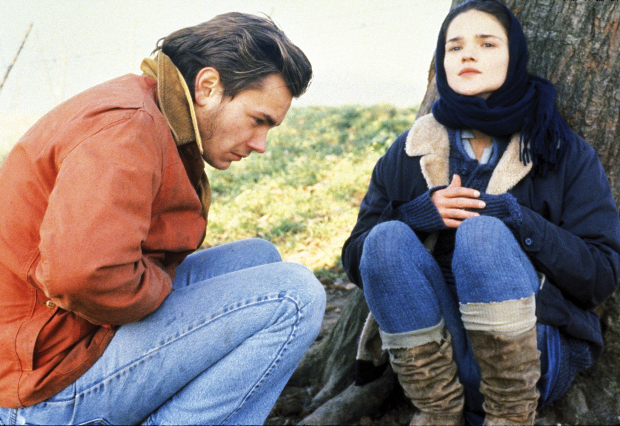 Mikey sitting with Carmella with warm winter clothes next to a tree.