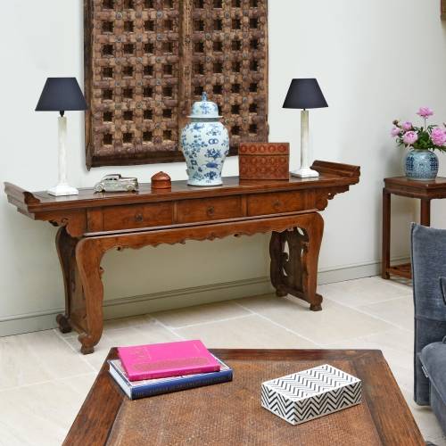 An antique Chinese altar table in an Oriental Eastern living room with Indian doors mounted above as wall art