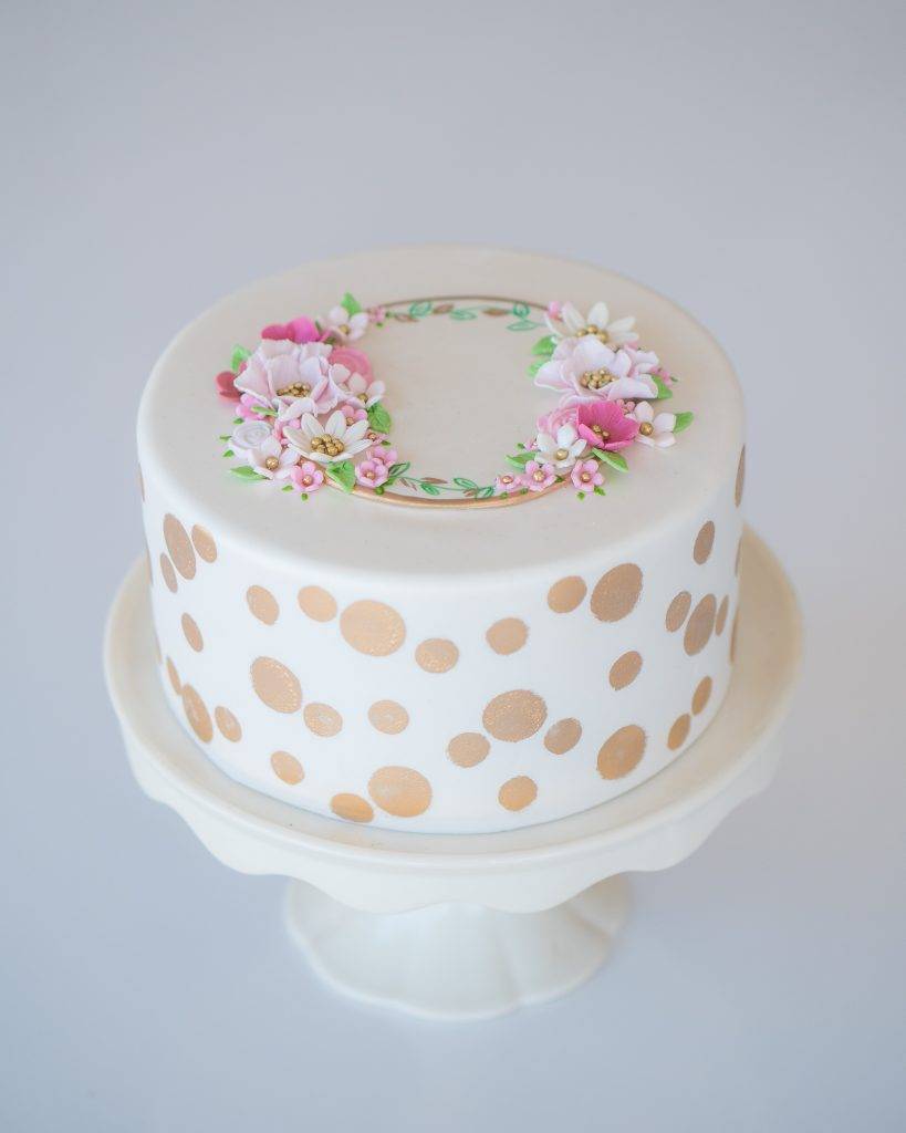 Birthday cake with a circle of flowers on top and gold polka dots