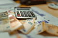 Plusieurs factures, une calculatrice et des billets de banque sur une table