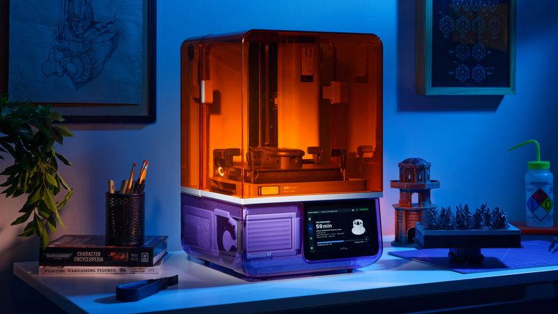 A 3D printer sits on a dimly lit desk.