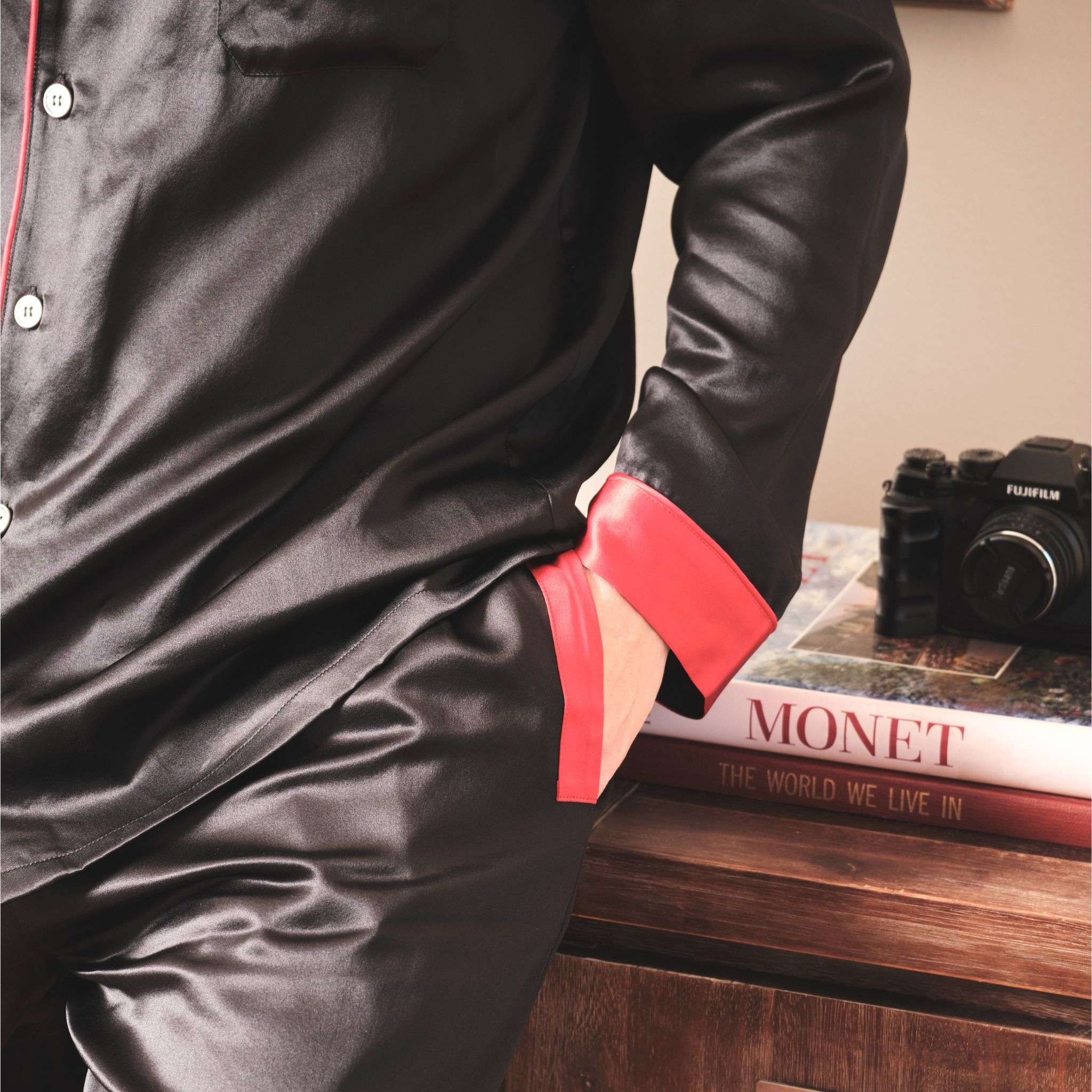 close up photo of the cuff and pocket region of a black silk pajama set worn by a model