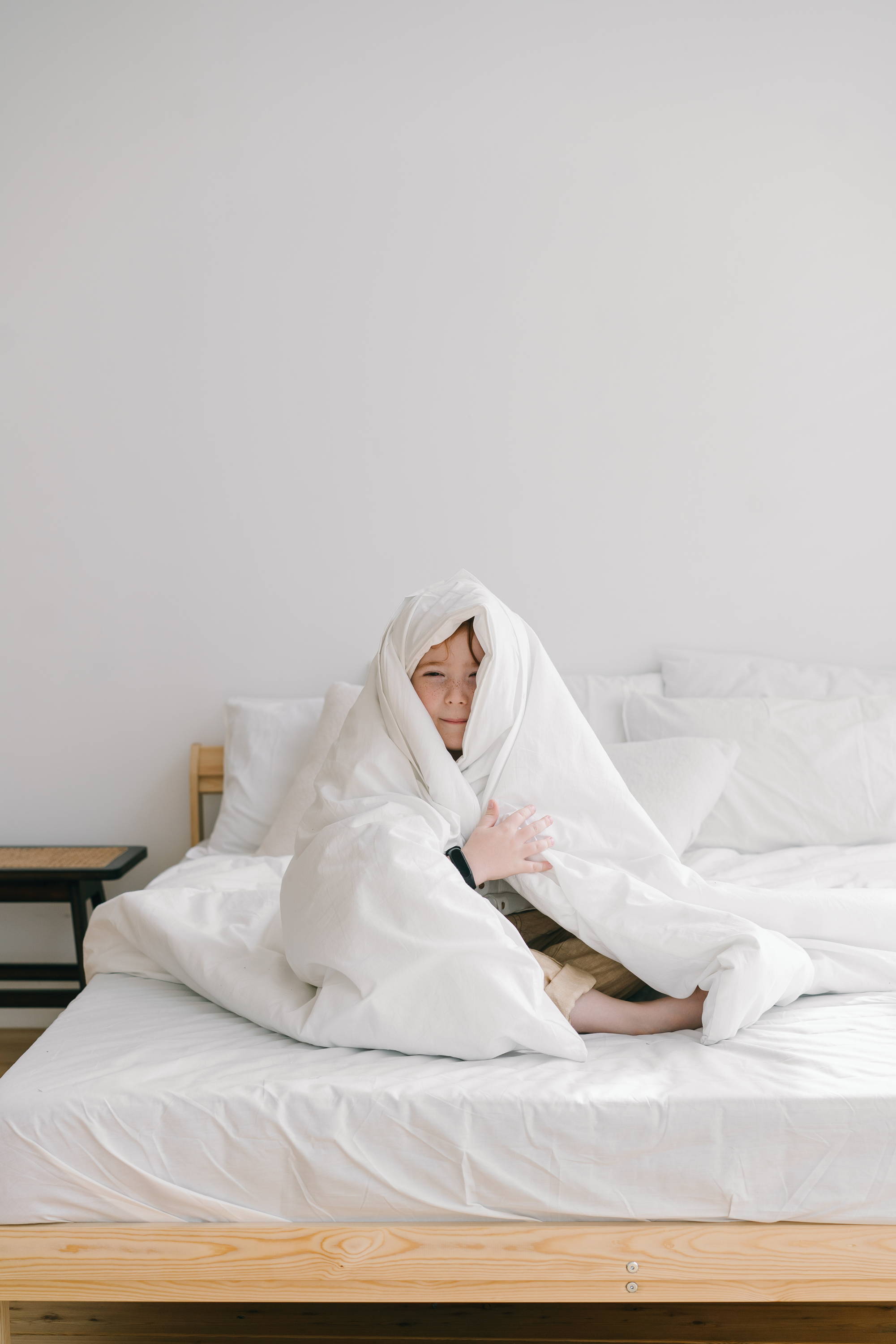 child wrapped in a blanket on bed