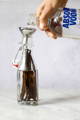 A person pours vodka into a glass bottle filled with vanilla beans