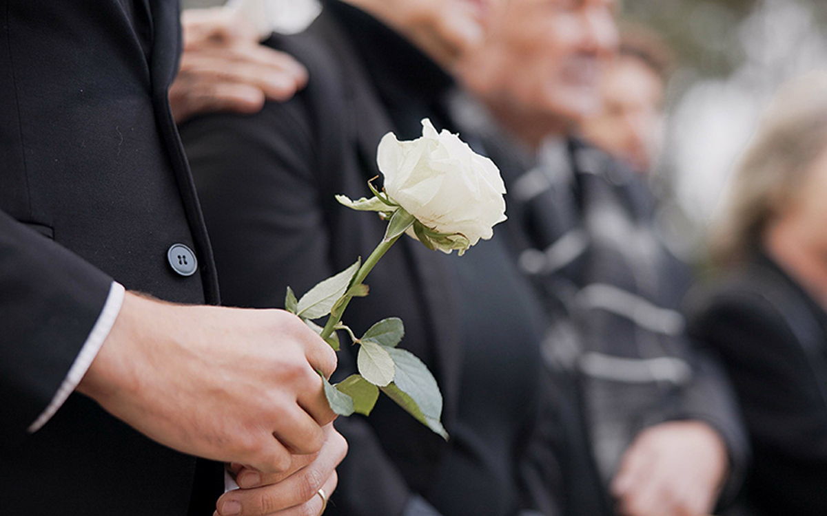 die Beisetzung im Sarg mit weißer Rose als Symbol des Abschieds