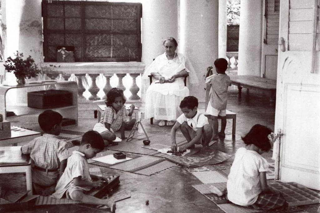 Maria Montessori watching children play in her class.