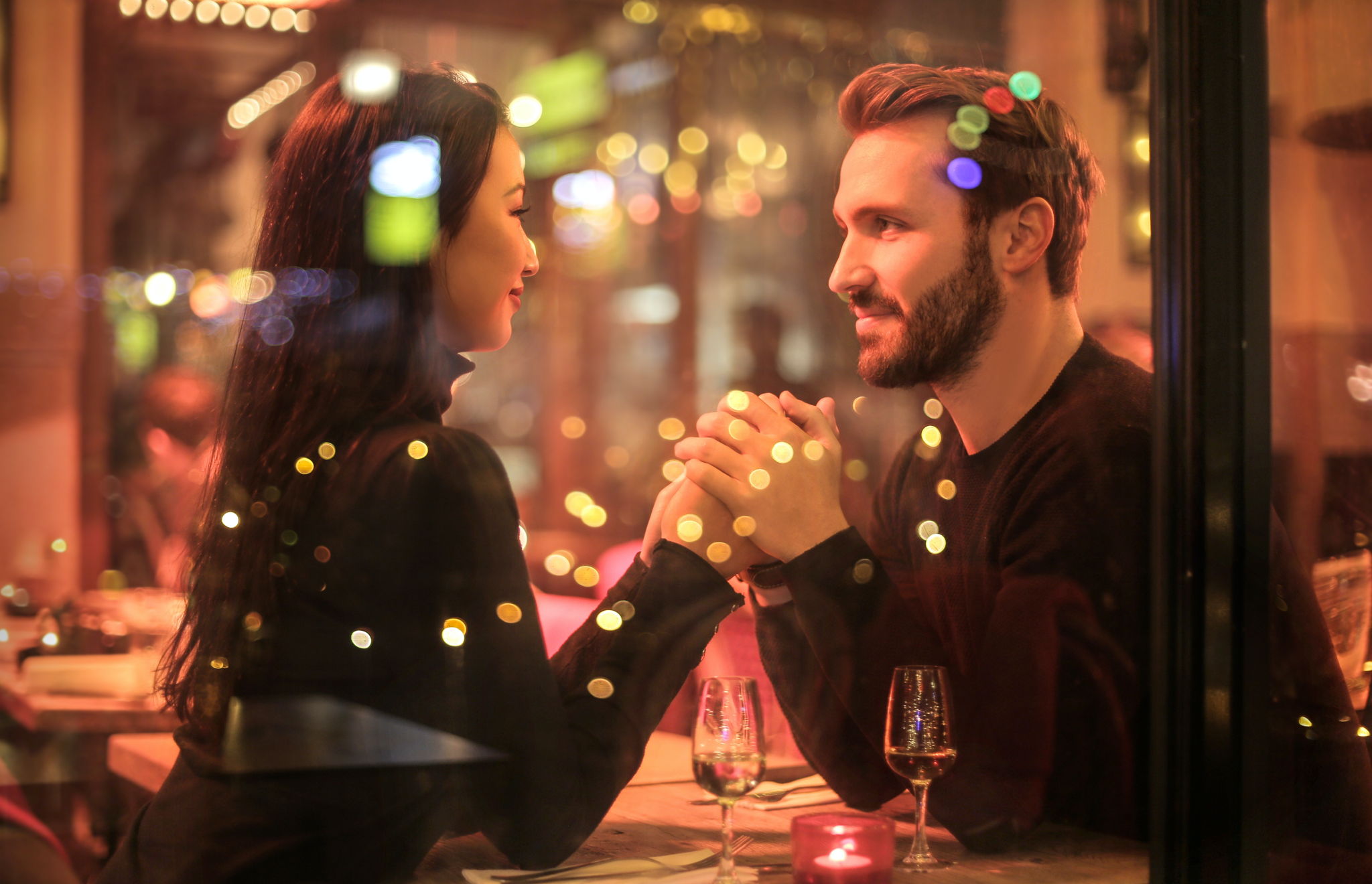 A multi ethnic couple have an intimate moment holding hands and looking into eachothers' eyes.