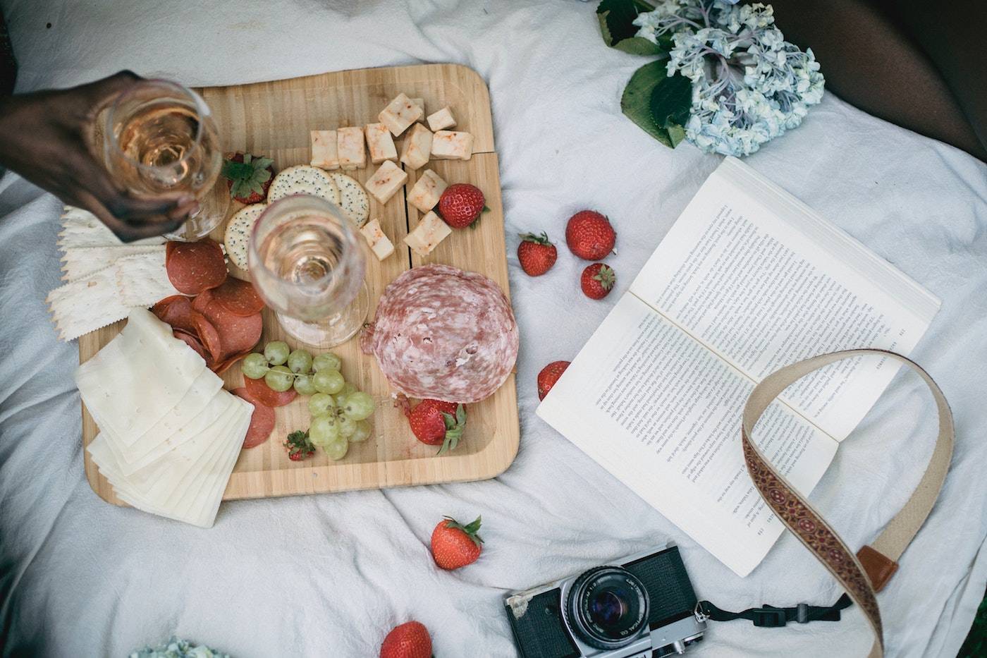 Platte paired with rose wine surrounded by green grapes, salami, strawberries and cheese.