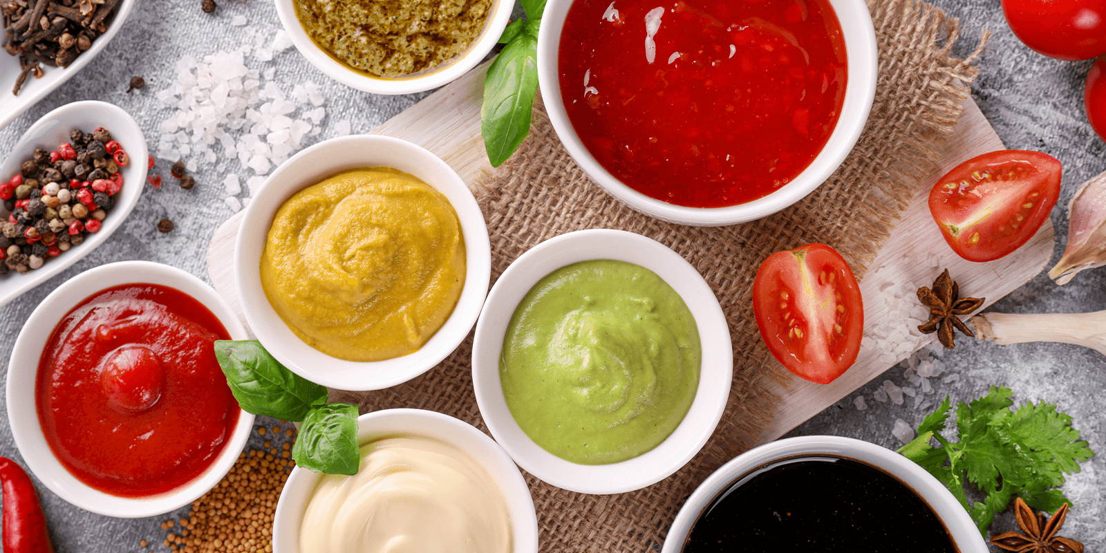 Bowls of condiments on a platter with fresh vegetables.