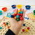 Woman holding dozen of multicolor beads above the Montessori Rainbow Beads game. 