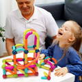 Little girl enjoying playing the Montessori Magnetic Set while being supervised by her grandpa.