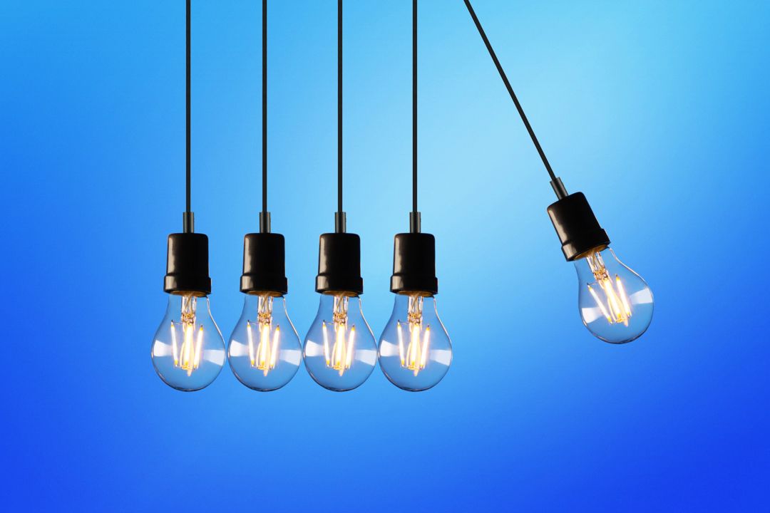Lightbulbs hanging on wires with one swinging