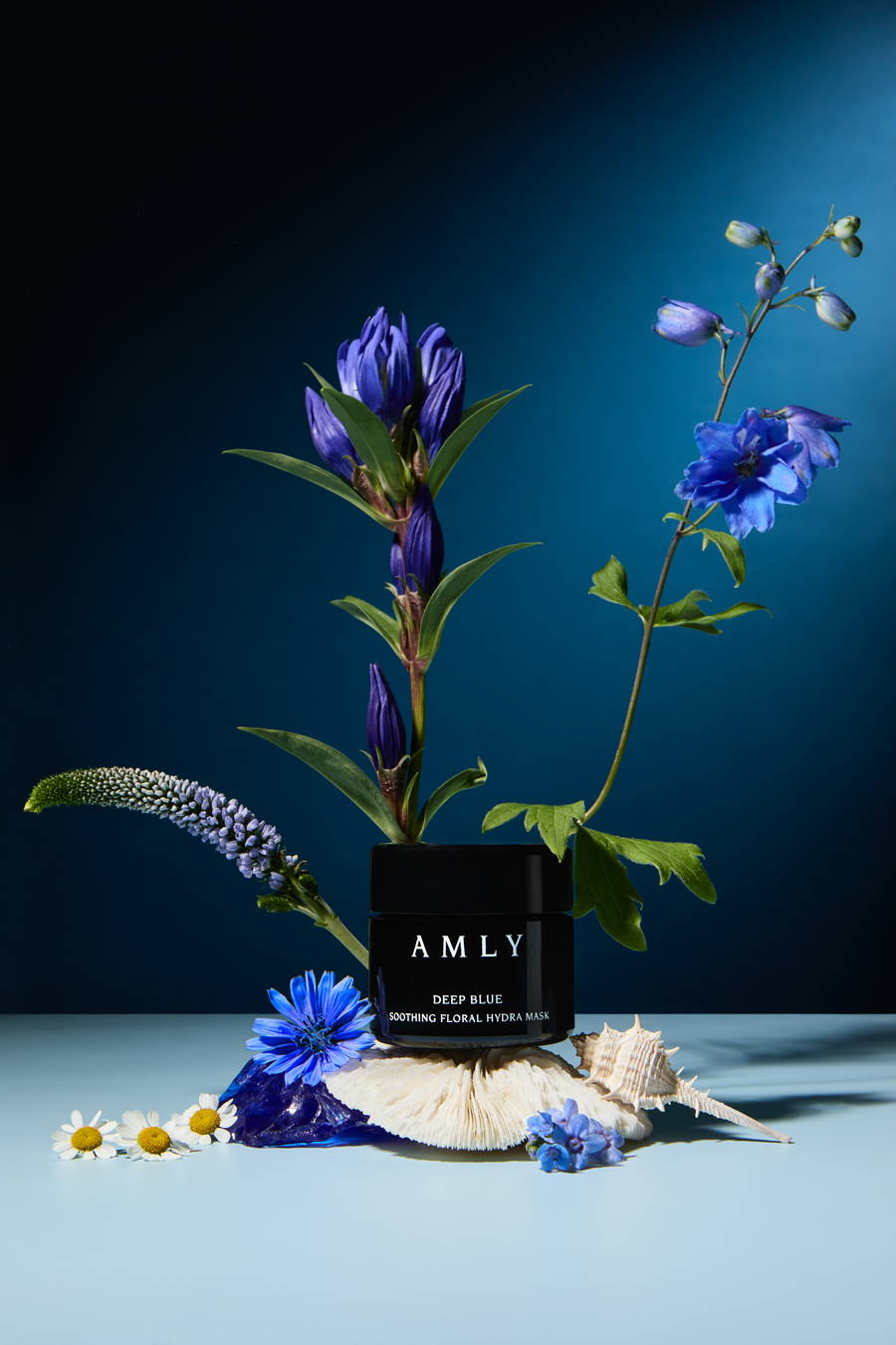 AMLY Deep Blue mask surrounded by flowers and shells on a blue background