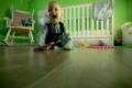 Little boy crawling in his green painted playroom. 