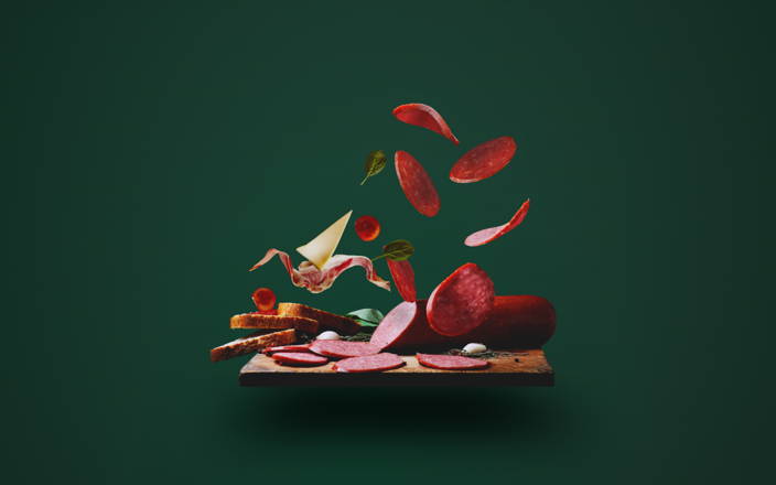 A charcuterie board with some of the meats and cheeses levitating above for Confetti's Virtual Charcuterie Board Class