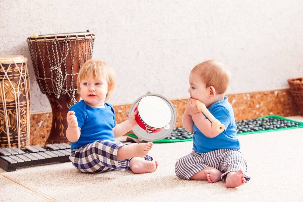 Two babies playing with percussion instruments.