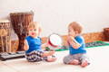 Two babies playing with percussion instruments.