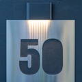 close up shot of the Lisse wall light by Havit illuminating the signboard at the front of the house