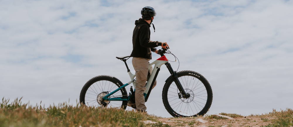 a man in a black hoody riding a full suspension Cannondale Moterra electric mountain bike
