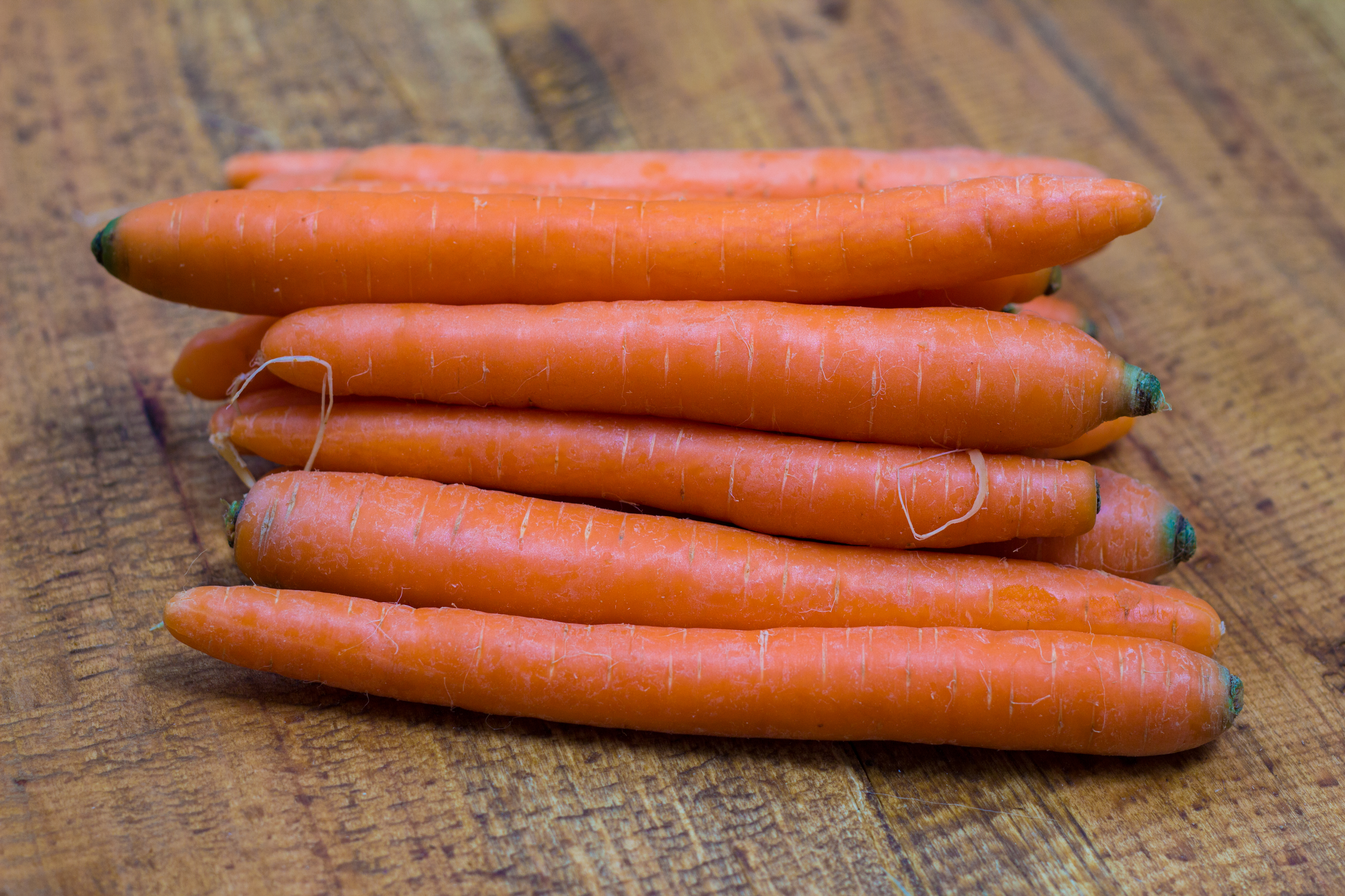 A stack of fresh orange baby carrots on a wooden background