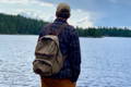 man in a blue flannel wearing the north bay daypack looking out at a lake