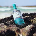 Bouteille de Tyree Gin posée sur le rivage près de la distillerie Isle of Tiree sur l'île de Tiree dans les Hébrides intérieures d'Ecosse