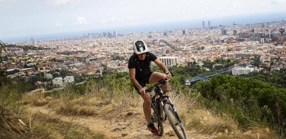 Un ciclista, en la ruta del Parque Natural del Collserola y al fondo, Barcelona.