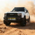 white 2024 toyota land cruiser with light bars in the grille and ditch lights for off roading by mandt automotive