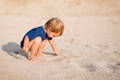 Little boy playing with sand on the beach.