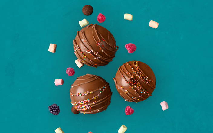 A birds eye view of three chocolate balls topped with sprinkles, surrounded by marshmallows and berries for Confetti's Virtual Chocolate Class