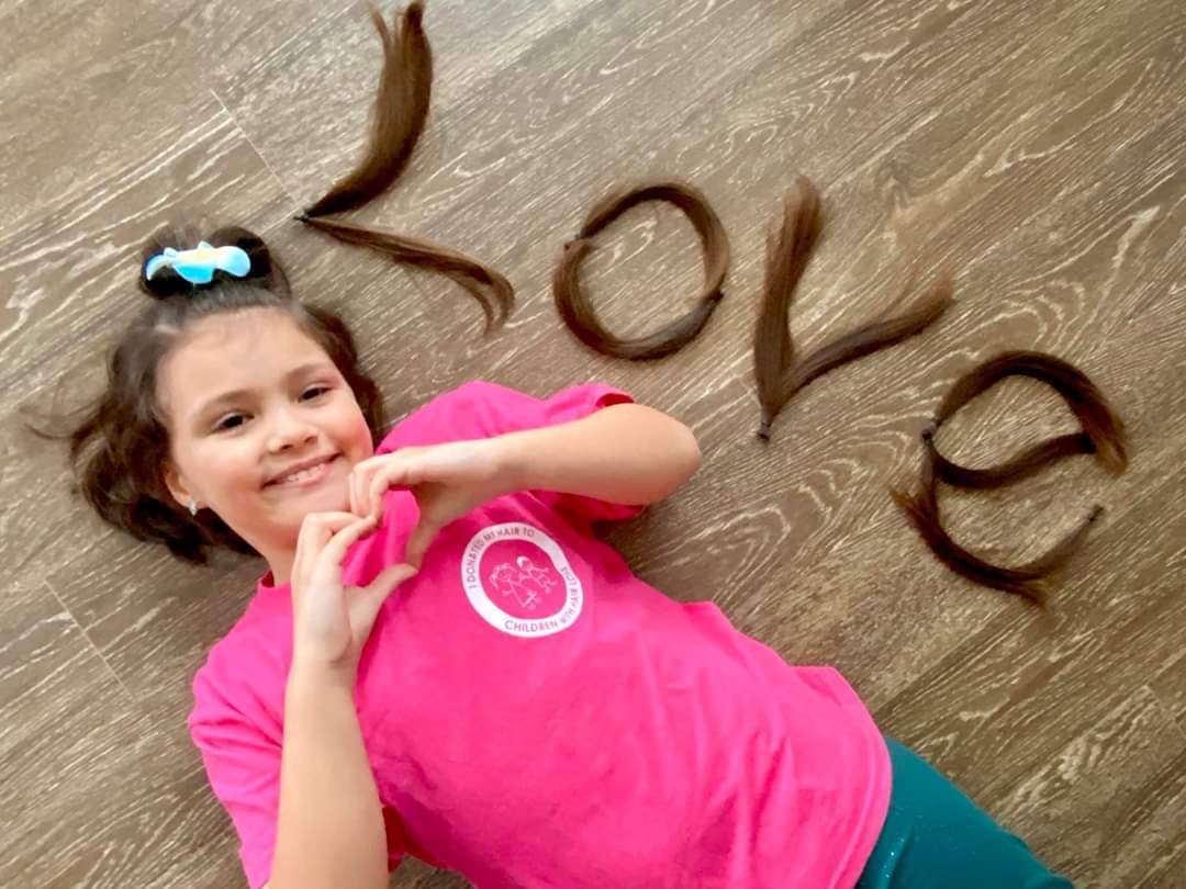 a girl laying next to hair arranged into the the word “love”