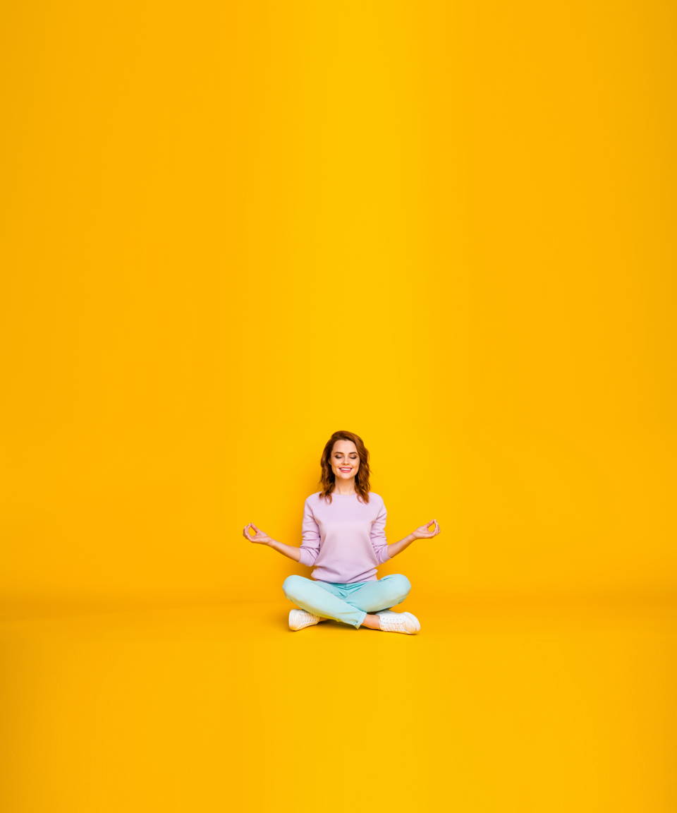 A smiling woman in a seated Sukhasana pose for Confetti's Virtual Yoga Class