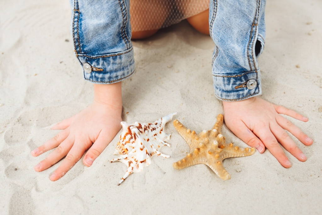 Girl kneeling close to two sea stars.