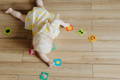 Toddler laying on the floor and playing with colorful puzzles.