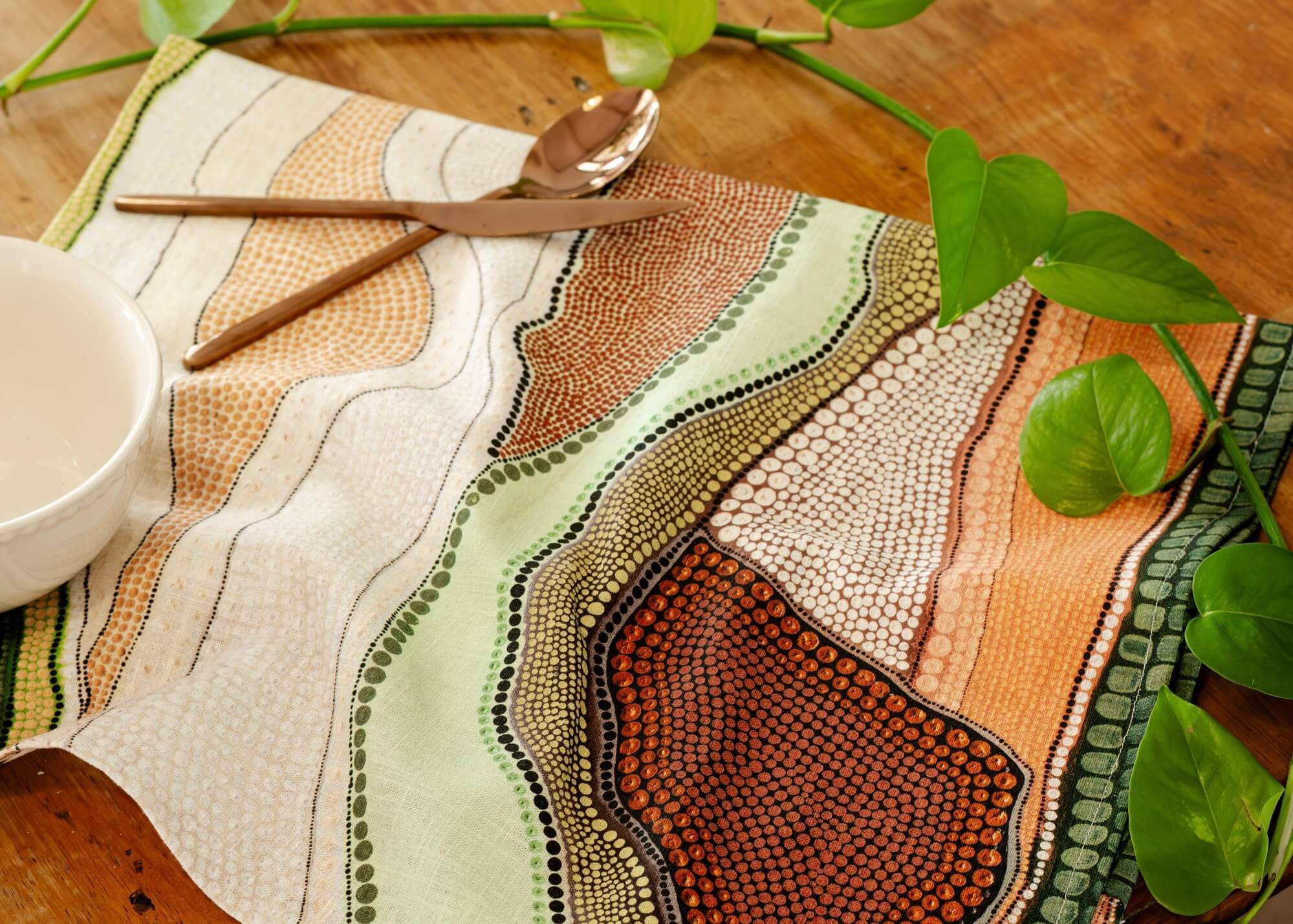 Linen tea towel on a wooden table made with an Aboriginal design