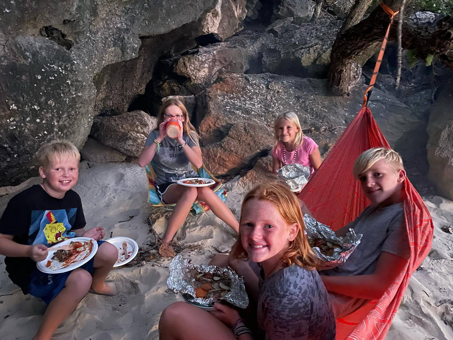 Crew eats a meal while seated in a hammock, or on the Monarch chair, or on rocks