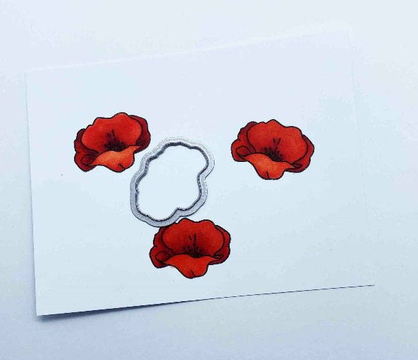 Three stamped poppies have been coloured in using a red alcohol marker pen