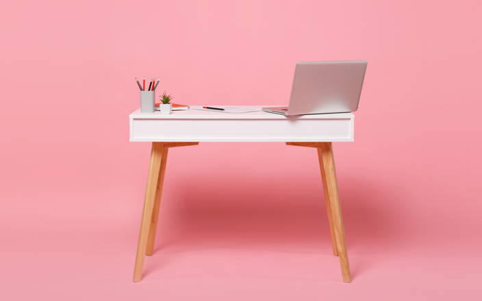 Desk with a laptop and office supplies against a pink background (preview)