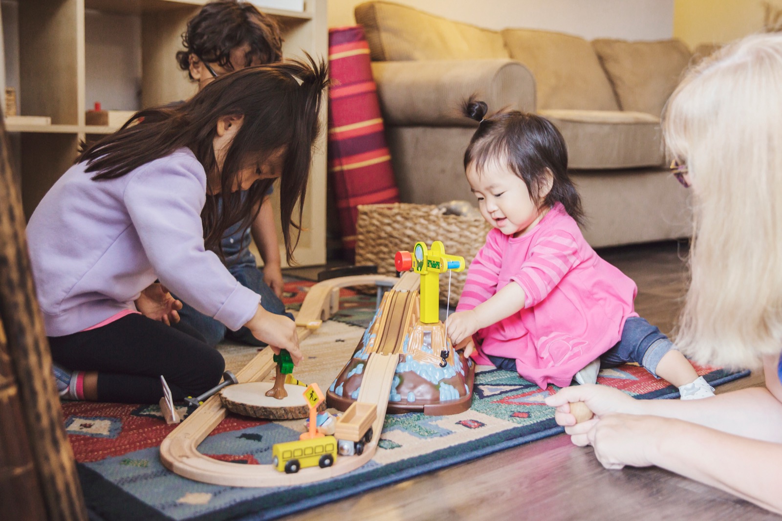 Children playing with a wooden train set in a home childcare setting