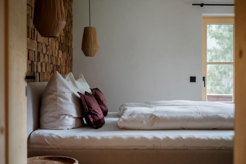 Schlafzimmer mit Doppelbett, Holzpaneelwand und warmem Licht im Apartment von Hugo & Pepi in Mittelberg.