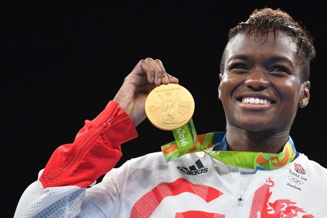 Nicole Adams smiling proudly holding her gold olympic medal to the audience.