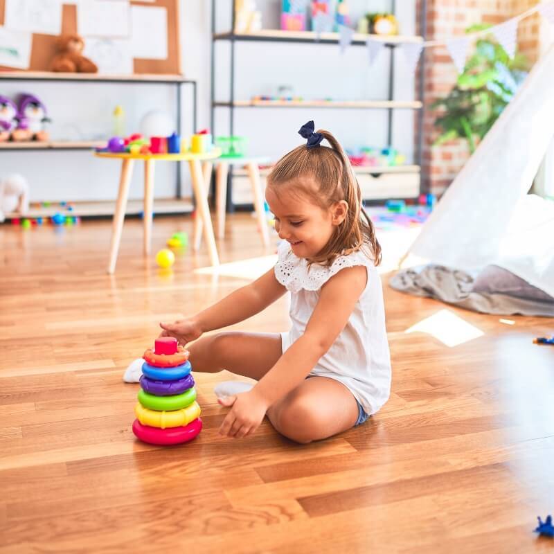 Little girl playing with her stacking rings in the playroom.