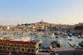 Vue panoramique sur le port de Marseille avec ses bateaux et une colline avec une cathédrale au sommet