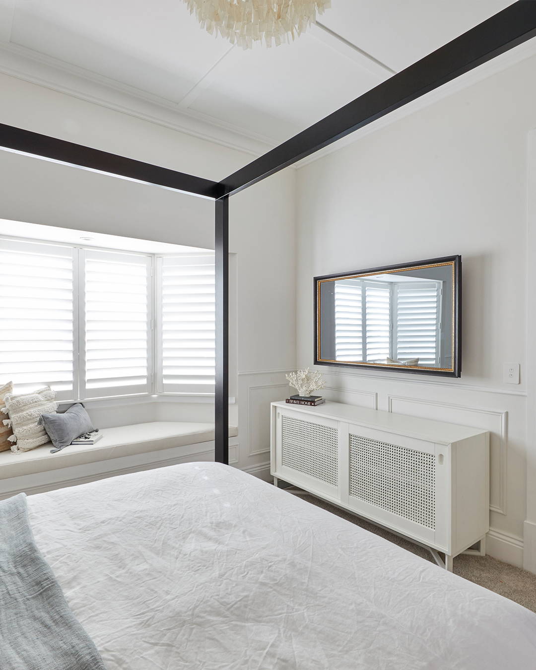 A TV-Mirror in a black and gold frame in a light-filled bedroom setting.