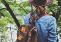 close up of a woman wearing a summit expedition pack and a hat out in the woods