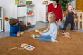 Montessori teacher watching children play with wooden toys.