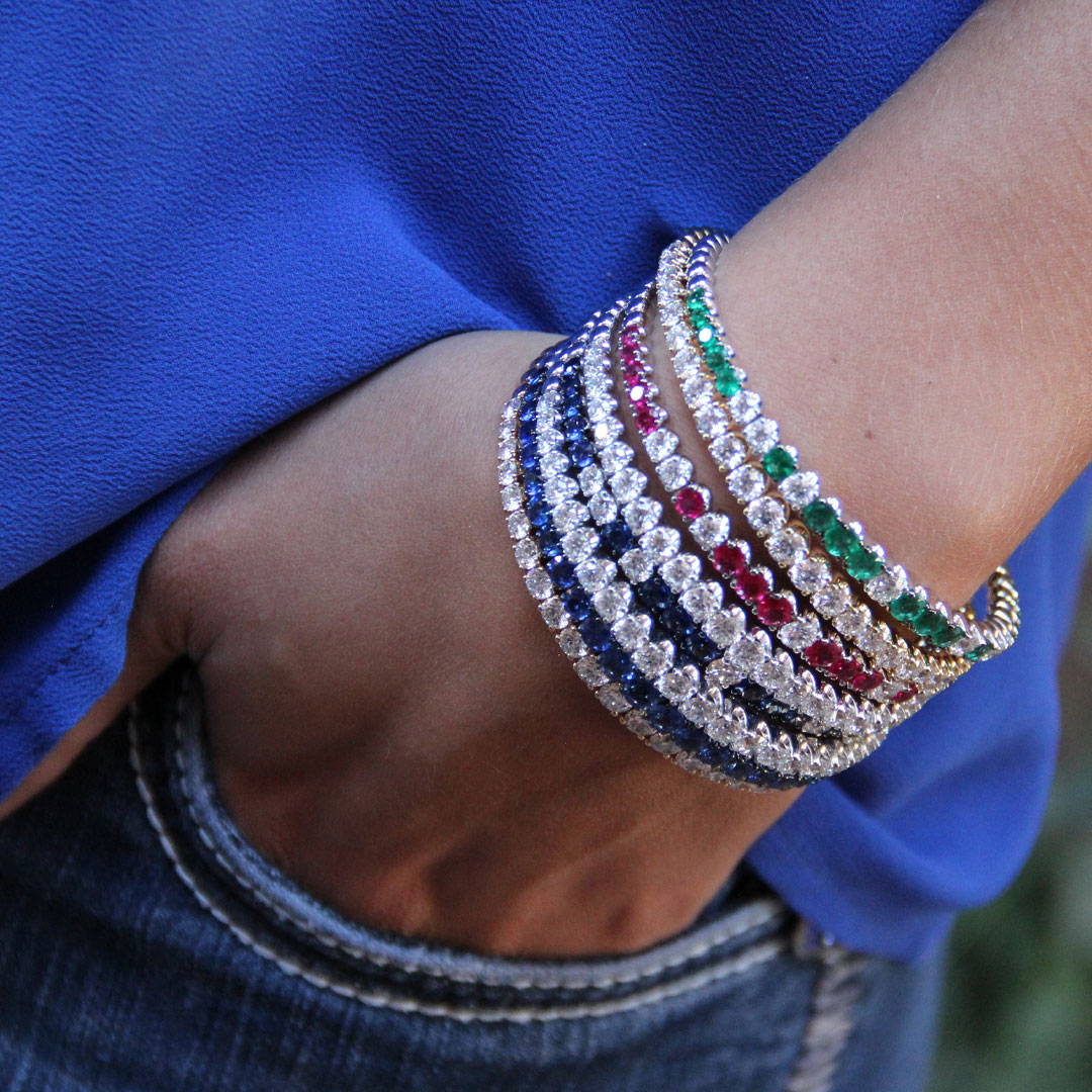 multicolored gemstone and diamond bracelets on the wrist of a girl with her hand in her pocket