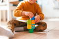 Toddler playing with colorful wooden blocks by stacking them. 